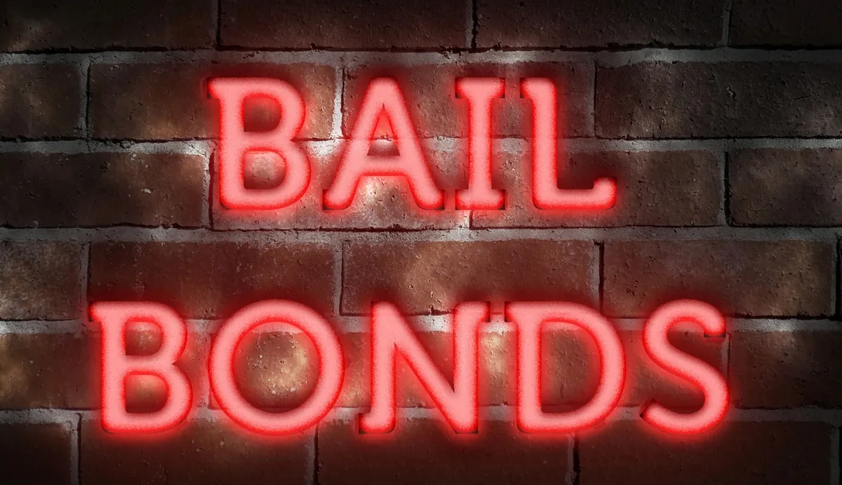 A red neon sign reading BAIL BONDS on a dark brick wall.