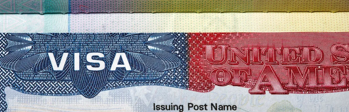 Close-up of a U.S. visa page in a passport, showing the word VISA and part of the red and blue printed design.