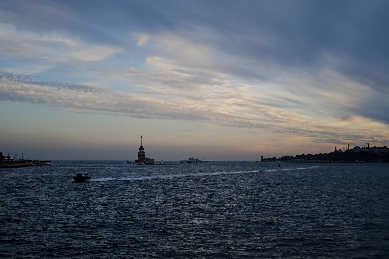 Maiden's Tower and boats on the Bosphorus at dusk, with the old city on the horizon.