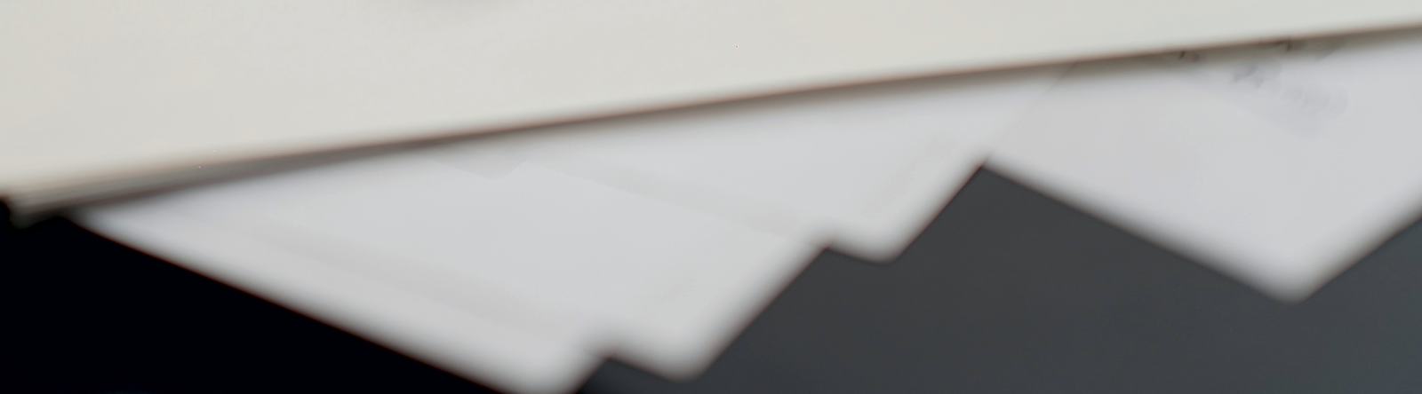 Loose sheets of paper and an envelope on a dark desk, soft focus.