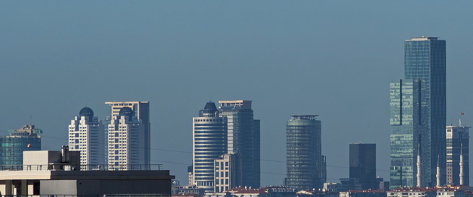The towers of Istanbul's Levent and Maslak business districts above red-tiled rooftops.