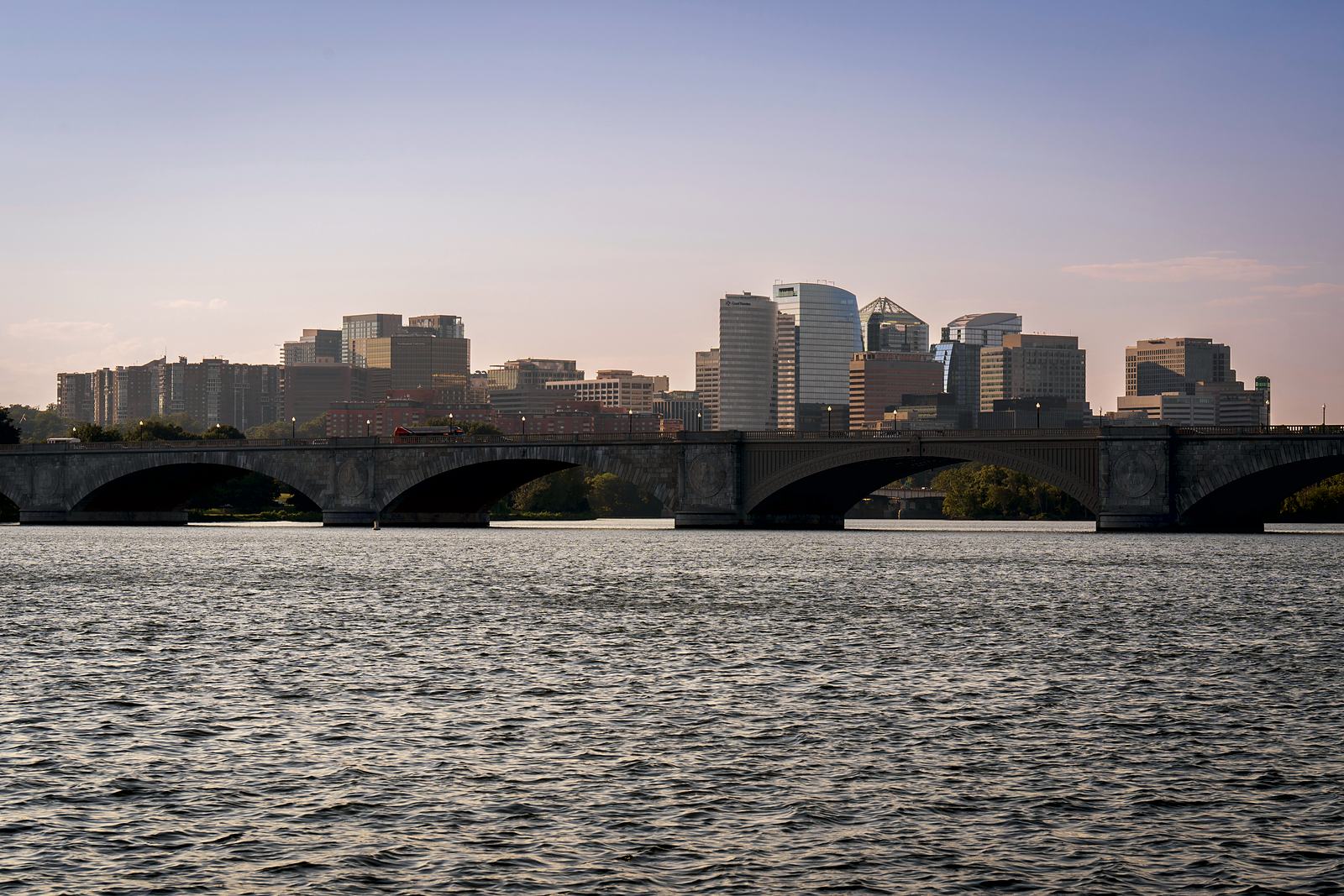 Arlington Memorial Bridge across the Potomac River, with the Virginia skyline behind it at dusk.